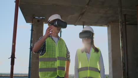 A-man-and-a-woman-engineers-at-a-construction-site-in-VR-glasses-manage-the-construction-of-a-building-discussing-a-development-plan